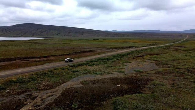 Aerial tracking shot of a car on a lonely mountain gravel road in Iceland