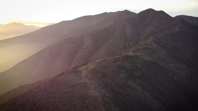 Circuling drone shot of hikers on top of a hill during sunrise in the misty mountains of Lima Peru