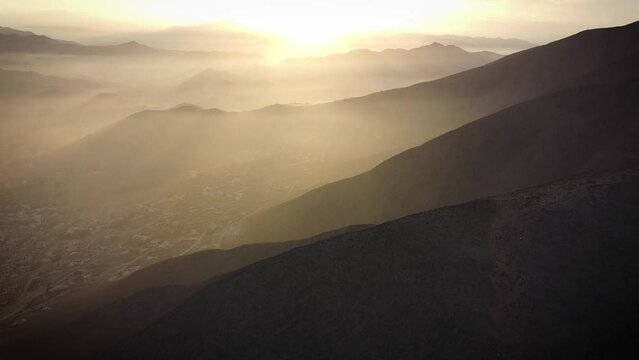 Drone shot of light beams in the misty hills of Lima Peru during sunrise
