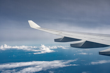 Wing of airplane above flat fluffy clouds surface with soft evening sunlight. Copy space.