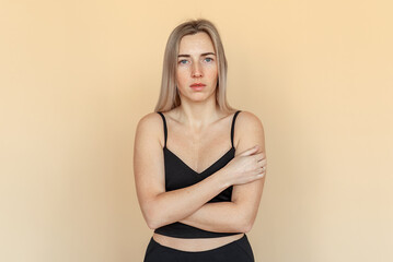 Portrait of the sad young woman thinking about relationships personal problems, standing over beige background. Upset girl lost in thoughts feel lonely depressed pondering or mourning