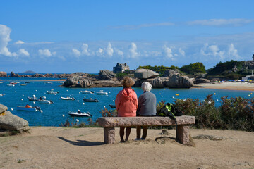 Deux personnes assises sur un banc face  à la mer à Trégastel en Bretagne