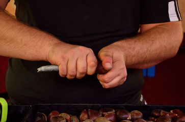 hands peeling or cutting roasted chestnuts
