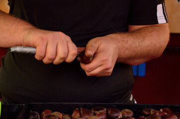 hands peeling or cutting roasted chestnuts
