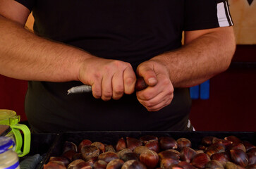 hands peeling or cutting roasted chestnuts
