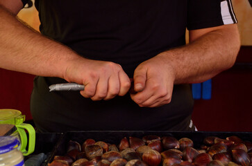hands peeling or cutting roasted chestnuts
