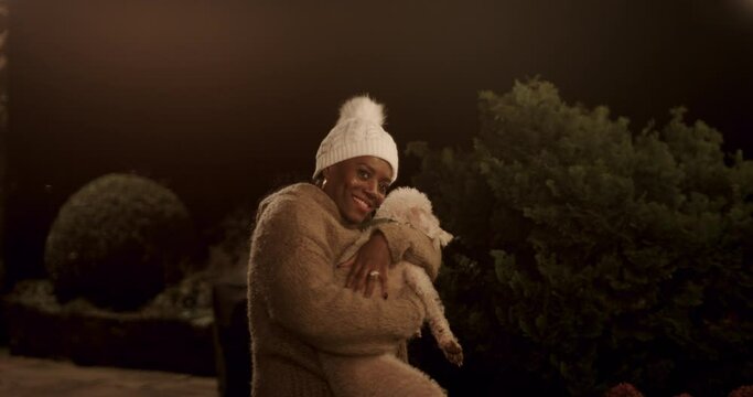 Portrait of smiling woman holding dog in backyard at night