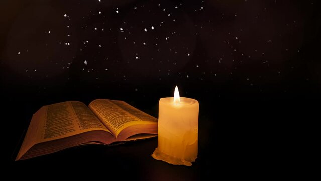 bible on the table in the light of a candle
