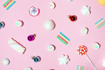 Gummy candies, jelly sweets, lollipops and Christmas baubles, creative winter holidays pattern, baby pink background. 