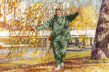 Mature woman in a green sweatshirt on a walk in the autumn park. Digital detox,.