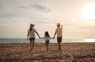 Happy asian family enjoy the sea beach at consisting father, mother and daughter having fun playing beach in summer vacation on the ocean beach. Happy family with vacations time lifestyle concept.