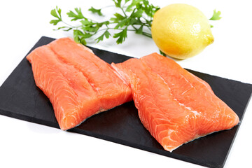 Salmon, fresh raw fish fillets with parsley and lemon on a slate