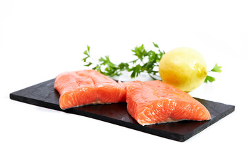 Salmon, fresh raw fish fillets with parsley and lemon on a slate