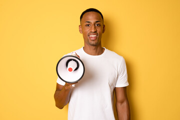 Young happy handsome african man holding megaphone isolated over yellow background.