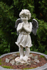 A wet statue of a little angel in the garden of a convent in the Russian city of Volkhov.