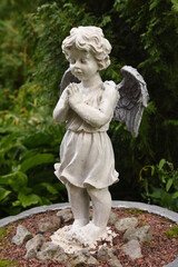 A wet statue of a little angel in the garden of a convent in the Russian city of Volkhov.