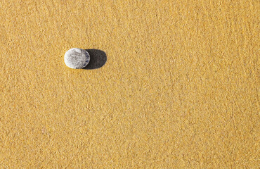 Fototapeta na wymiar Round grey sea stone on beach sand as background. Copy space. Top view.