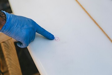 Close up of hands pointing out the damaged part to repair on a surfboard