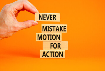 Mistake or action symbol. Concept words Never mistake motion for action on wooden blocks. Businessman hand. Beautiful orange table orange background. Business mistake or action concept. Copy space.