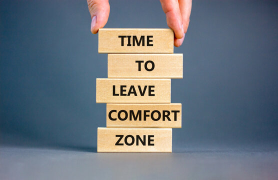Leave comfort zone symbol. Concept words Time to leave comfort zone on wooden blocks. Businessman hand. Beautiful grey table grey background. Business time to leave comfort zone concept. Copy space.