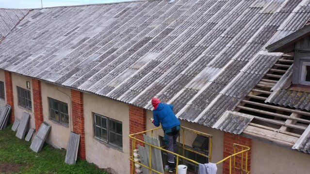 Roof fixing, filling holes with caulking gun using sealant, aerial view