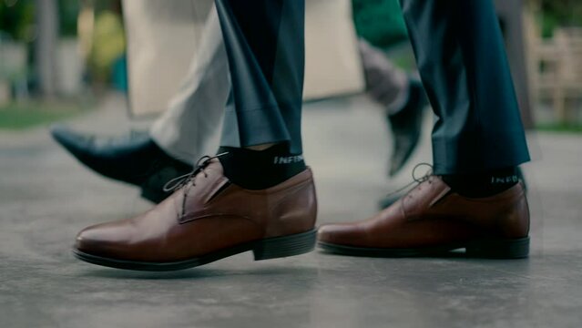 Legs of men wearing elegant shoes walking down the street. Close-up shot in slow motion