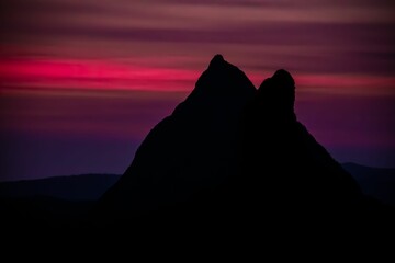 Silhouette shot of mount Beerwah in Glass House mountains under colorful sky, Australia