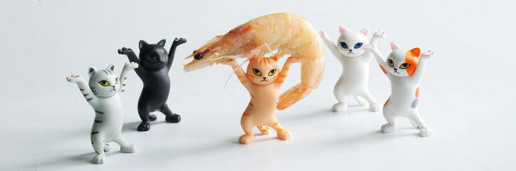 Funny toy dancing kittens and a big shrimp on a light background. A humorous business training concept. Concept of the effectiveness of teamwork and leadership in the working group.