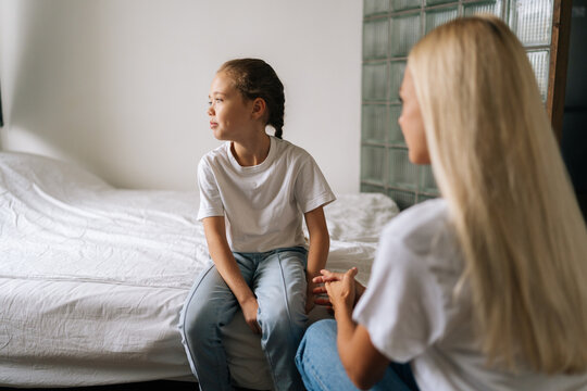 Back View From Unrecognizable Young Mother Talking Counseling Upset Offended Pretty Child Girl Feels Sad Insulted Sitting On Bed At Home. Concept Of Mom-children Problem In Preteen Years.