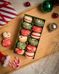 Schilderijen op glas Vertical top view of colorful macarons in the box on a wooden surface - Christmas sweets © Pjm Captures/Wirestock Creators