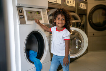 Pleased child posing for the camera at a self-service laundromat