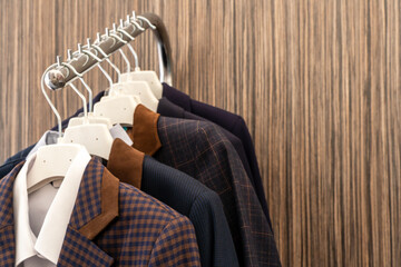 New business men's suits are hanging on hangers in the store. Modern fashionable clothes. A luxury store with mens clothing. Designer business suits