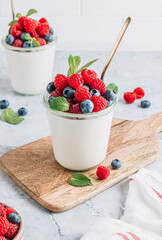 Delicious italian dessert panna cotta with fresh raspberry, blueberries and mint on gray marble background
