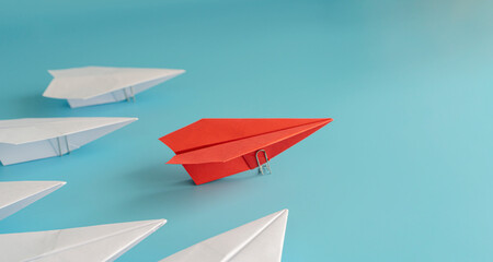 Fototapeta na wymiar Red paper plane leading a white paper plane on a blue background.