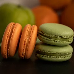 Tuinposter Close-up view of orange and green sweet French macarons © Pjm Captures/Wirestock Creators