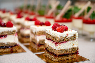 Close up of cakes with fresh fruits and berries arranged in a row on a party table