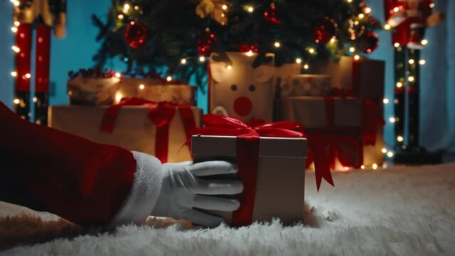 Hand of Santa Claus i deliver the Christmas gift box under the tree 