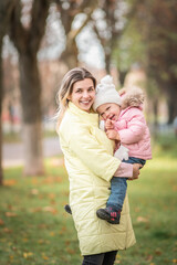 Fototapeta premium Portrait of a beautiful charming young mother with her daughter in the spring park.