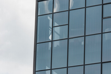 Modern business office exterior full of windows. Front side of a tall commercial building or work place
