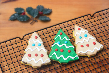 Butter cookies in the shape of a Christmas tree on a black grid with a wooden background, Christmas background, Christmas cookies
