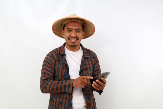Happy asian farmer standing while pointing his cell phone. Isolated on white background with copyspace