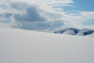 Empty hill under pure white snow in winter as copy space, mountain and clouds in background