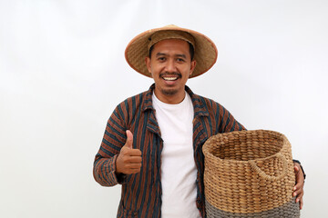 Fototapeta premium Happy asian farmer standing while holding an empty basket and showing thumbs up. Isolated on white background