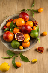 A variety of tropical citrus fruits on a ceramic plate, top view