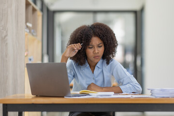 Obraz na płótnie Canvas Portrait of tired young business african american woman work with documents tax laptop computer in office. Sad, unhappy, Worried, Depression, or employee life stress concept