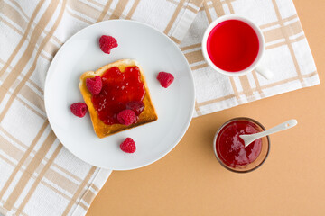 Cup of red tea and toasted bread with raspberry jam