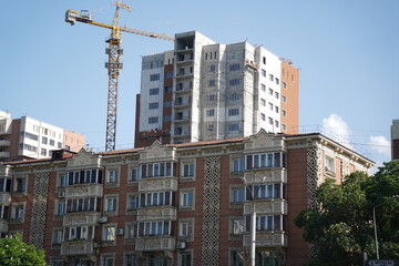 Fototapeta premium Almaty, Kazakhstan - 04.26.2022 : A residential building with an old design and a new residential complex under construction