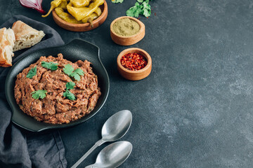 Mashed red bean with spices. Traditional georgian dish lobio in black plate with bread and pickled hot peppers.