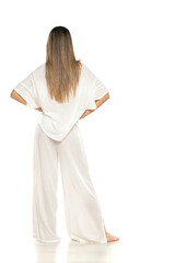 young modern barefeet woman in white pants and blouse posing on white background. back, rear view