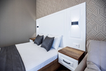 Modern Bedroom. The headboard of a large white double bed. Brown and white pillows.